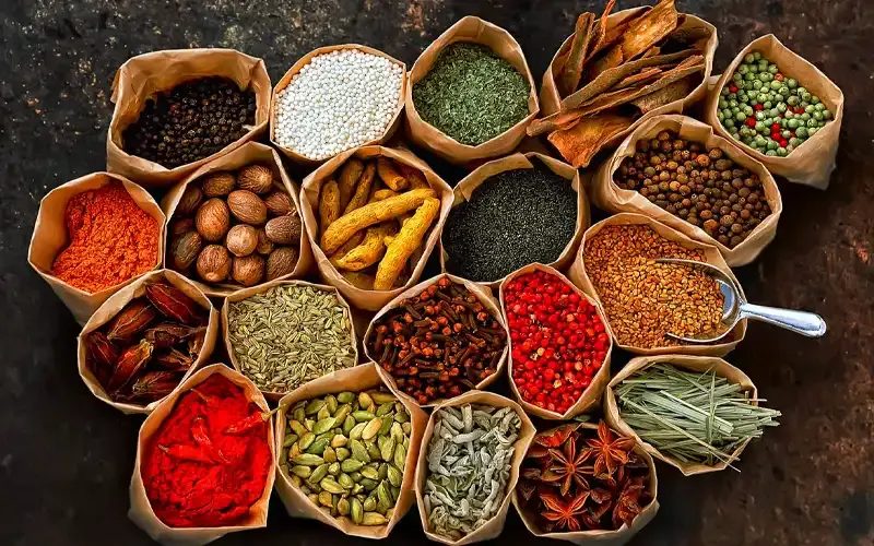 Sacks of spices and dried seeds packed side by side in a market.