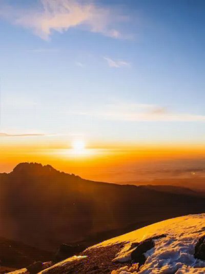 The sun rising over a rocky ridge above a sea of cloud.