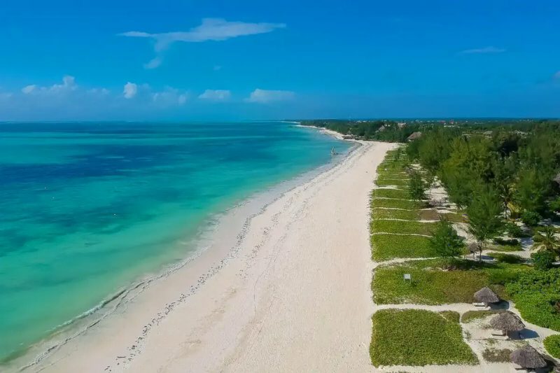 A long white beach and turquoise shallows seen from the air.